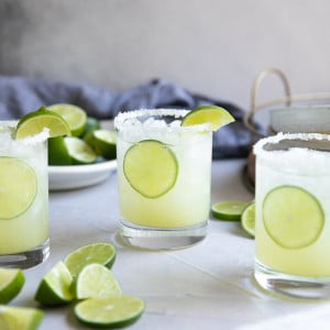 Three glasses filled with classic lime margarita on the rocks.