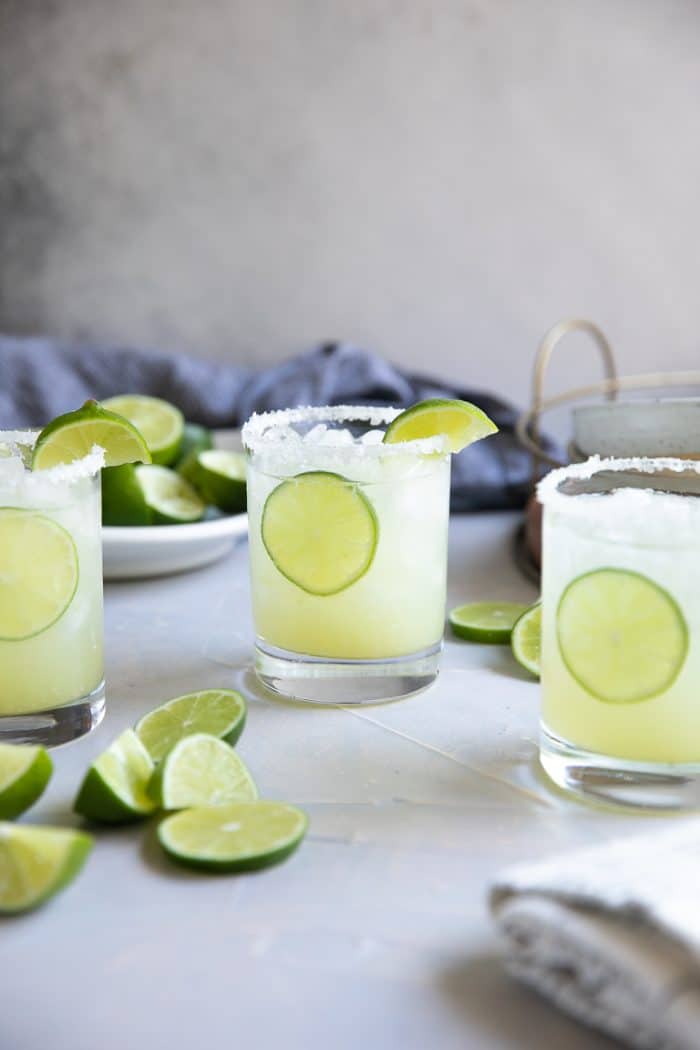 Three glasses filled with classic lime margarita on the rocks.