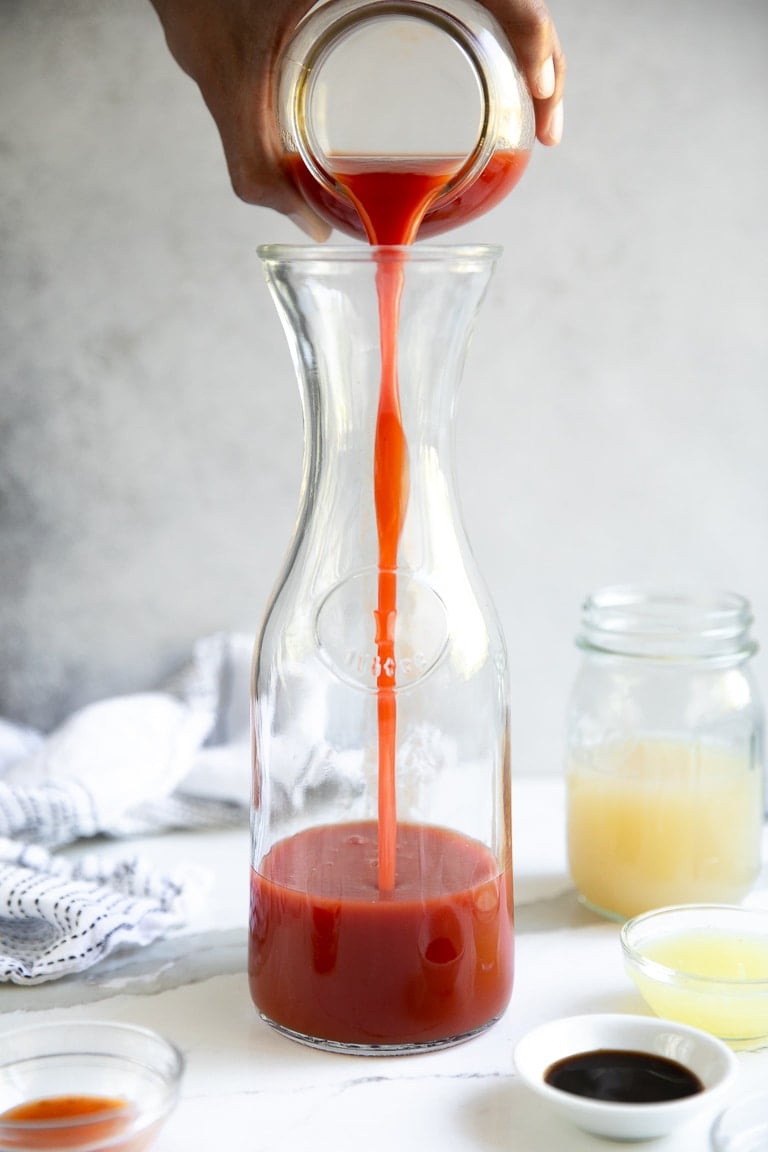 Tomato juice being poured into a large pitcher.