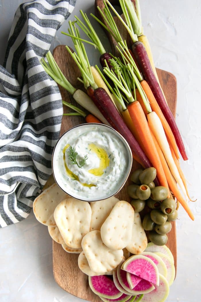 Snack board with bowl filled with creamy homemade tzatziki