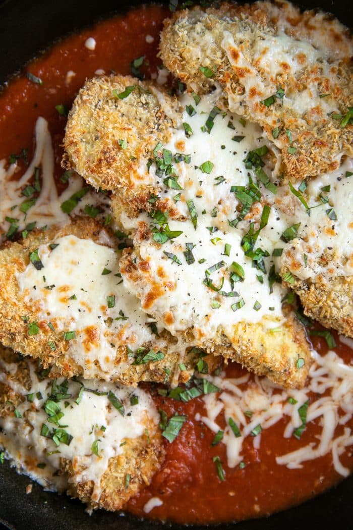 Baked chicken parmesan cutlets in a skillet with homemade marinara sauce, baked and covered with cheese.