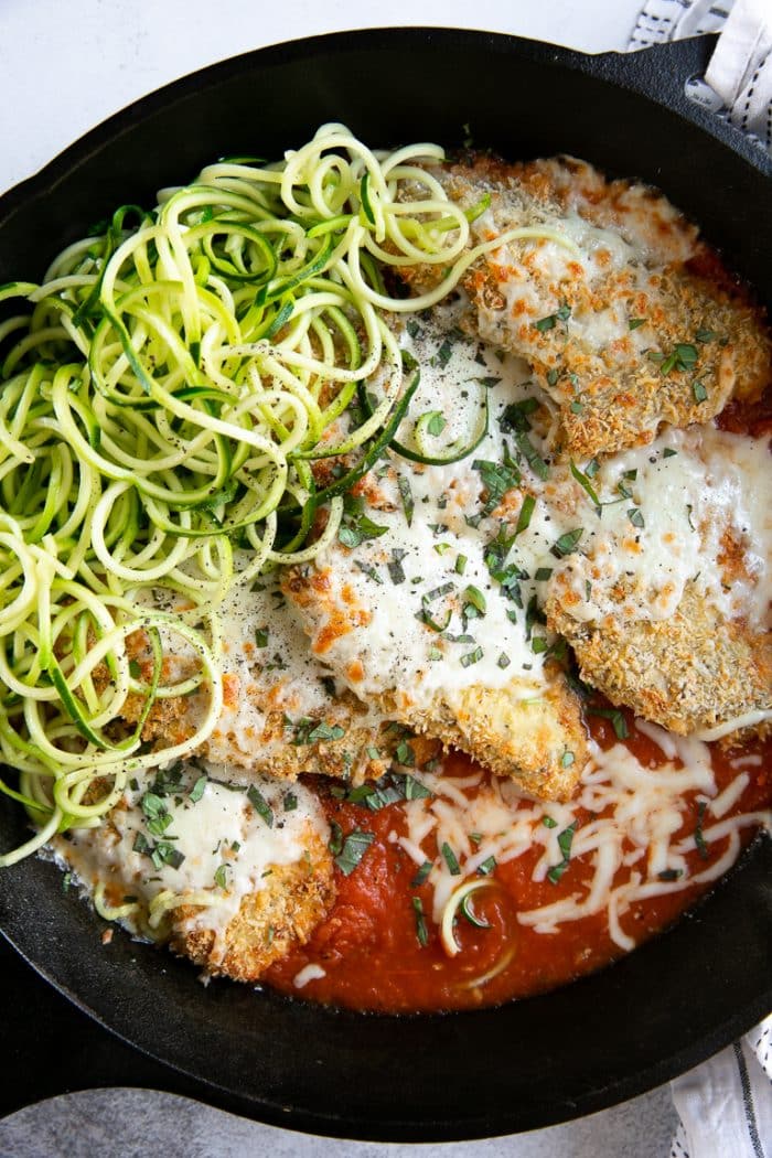 Baked chicken parmesan cutlets in a skillet with homemade marinara sauce, baked and covered with cheese.