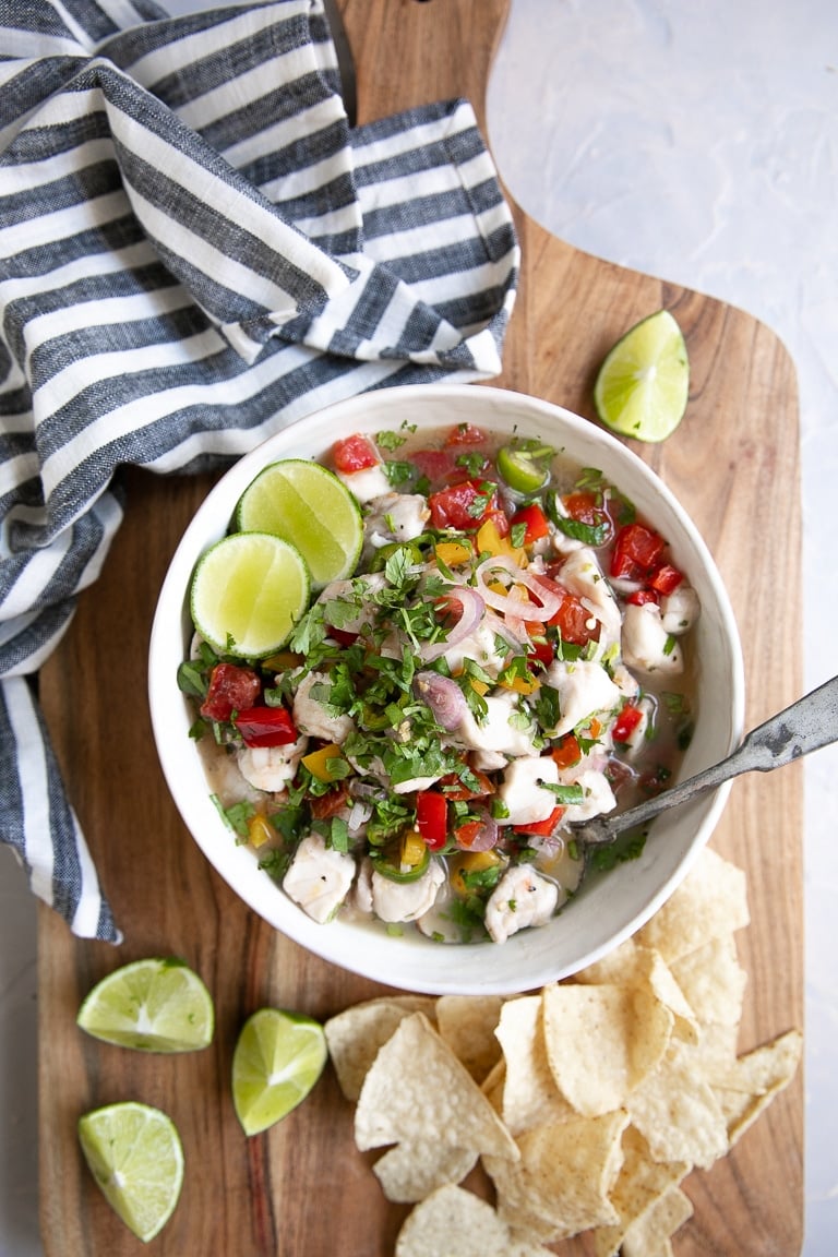 Overhead view of a white bowl filled with fish ceviche served with tortilla chips.