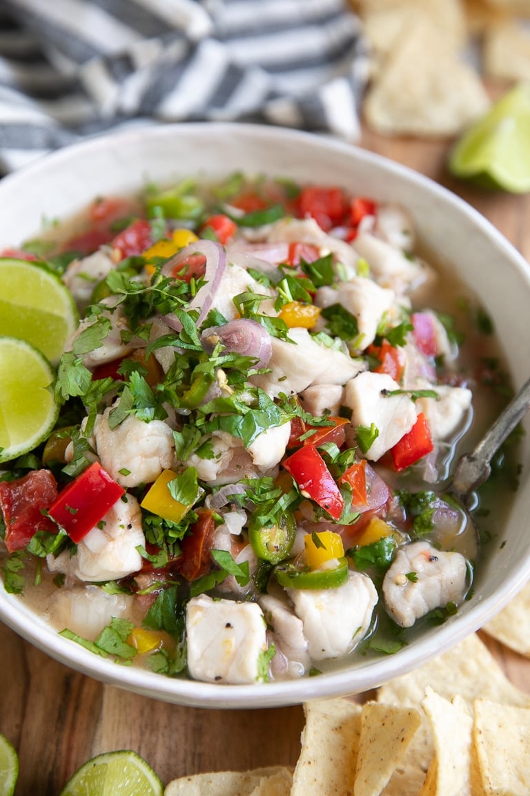 Large white shallow bowl filled with fish ceviche and garnished with fresh cilantro.