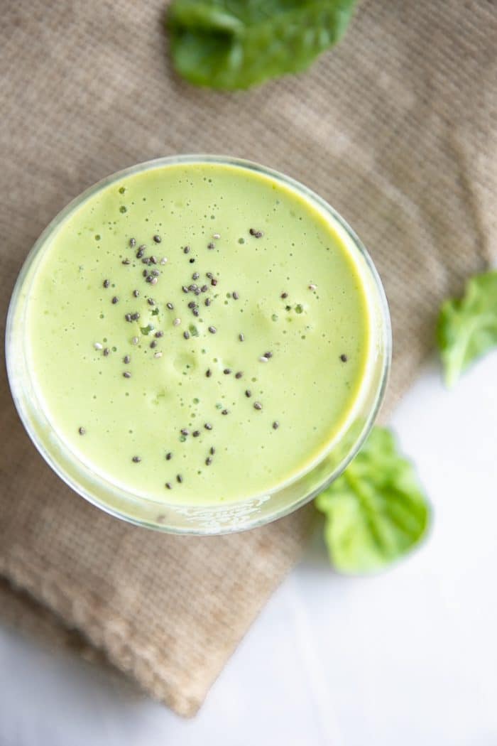 Overhead image of a single glass filled with a green smoothie sprinkled with chia seeds.