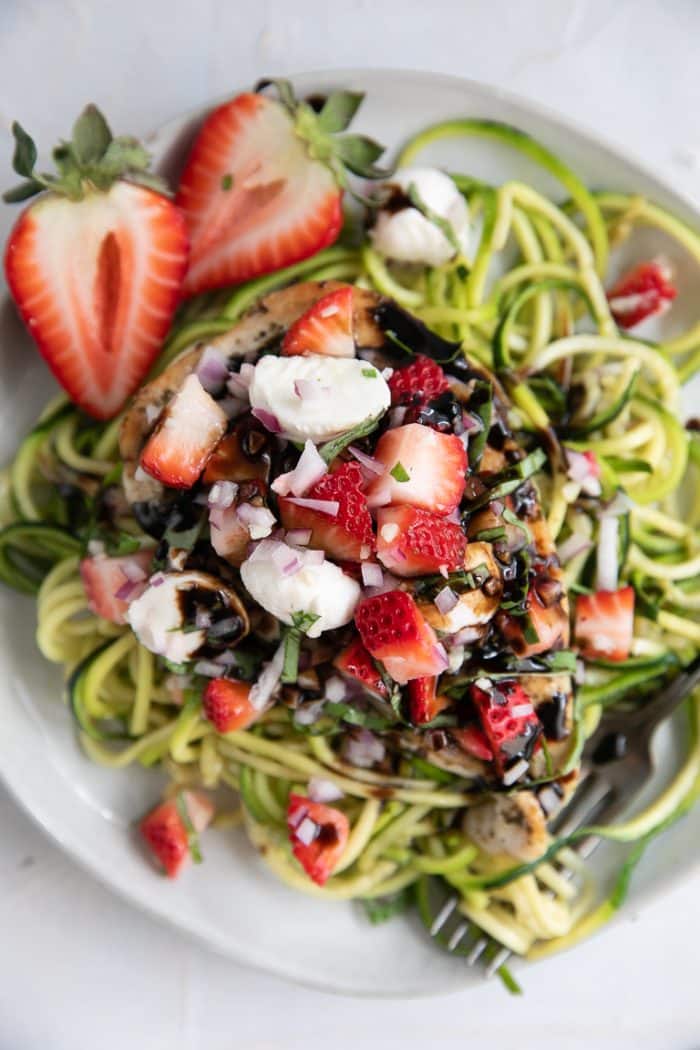 A bowl of strawberry bruschetta chicken on a plate, with zoodles