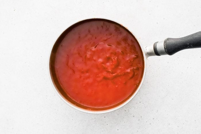 Homemade BBQ sauce simmering in a medium saucepan.