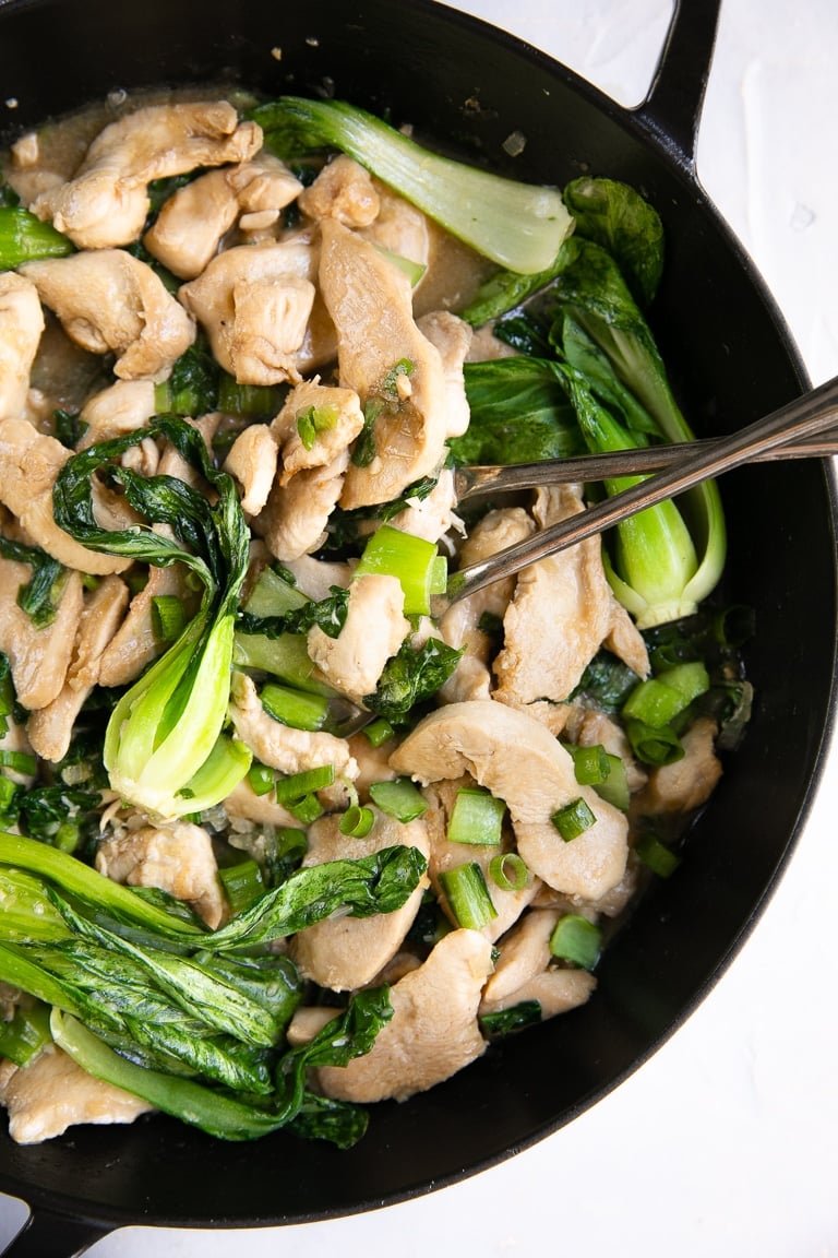 Skillet filled with stir fried chicken, baby bok choy, and green onions