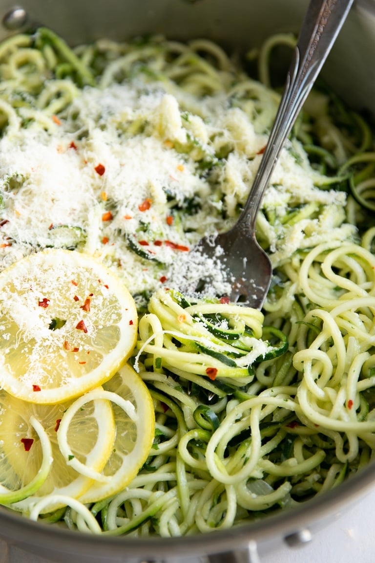 Skillet filled with zucchini noodles cooked with garlic and tossed with parmesan cheese.