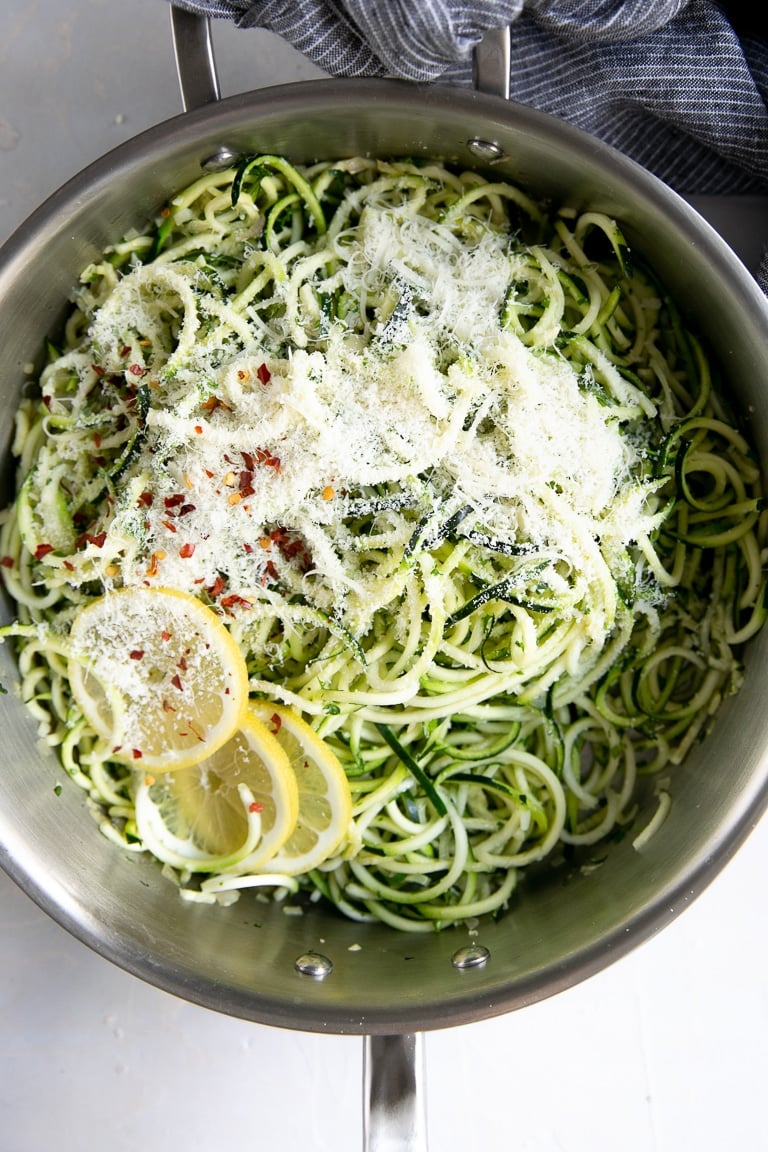 Skillet filled with zucchini noodles cooked with garlic and tossed with parmesan cheese.