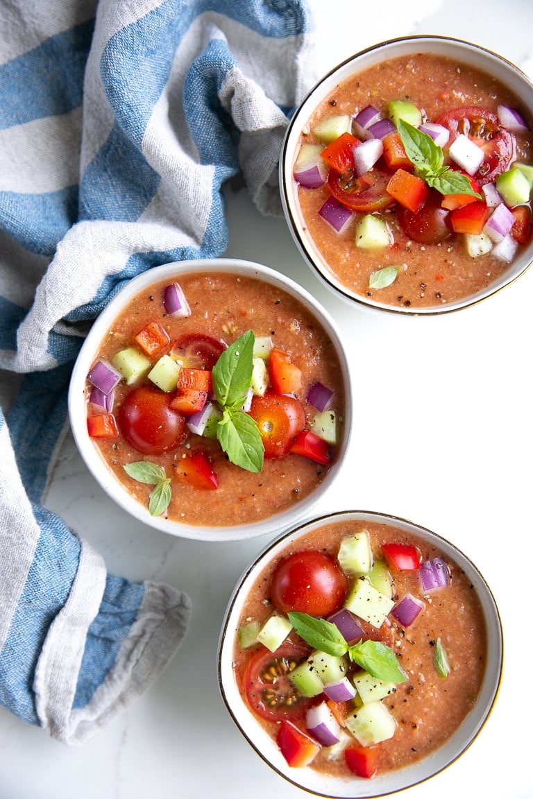 Birdseye view of three small bowls filled with summer gazpacho.