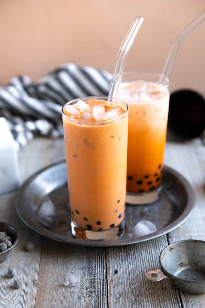 Two glasses filled with ice cold thai tea boba.