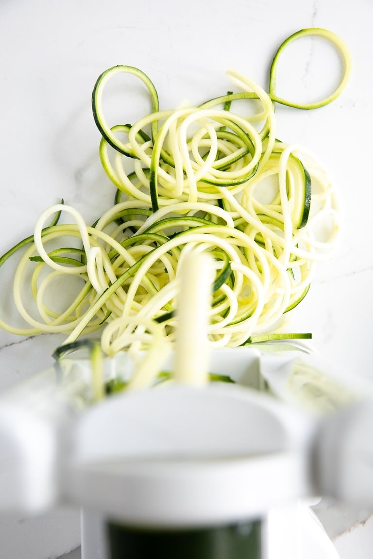 Zucchini being spiralized into zucchini noodles.