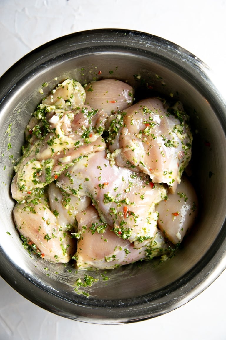 Chicken thighs marinating in chimichurri sauce.
