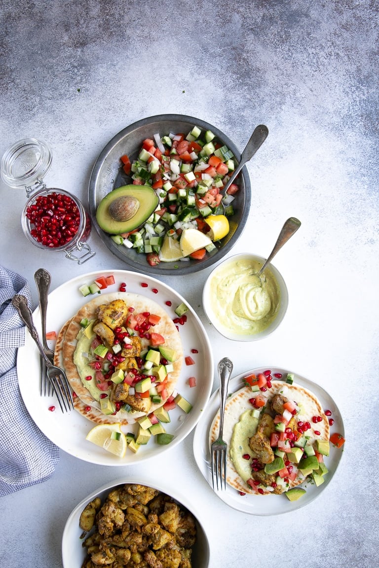 Overhead image of curry marinated chicken thighs with curried yogurt sauce on soft pita bread.