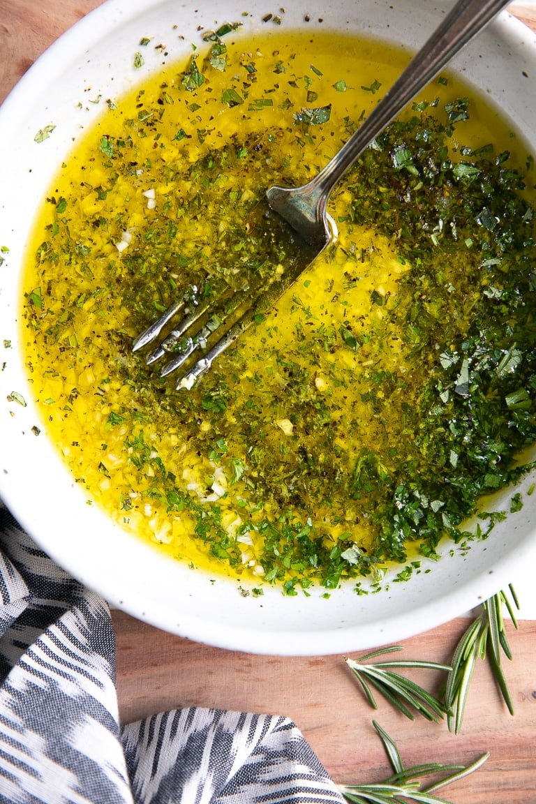 White shallow bowl filled with mixed together ingredients for Greek chicken marinade.