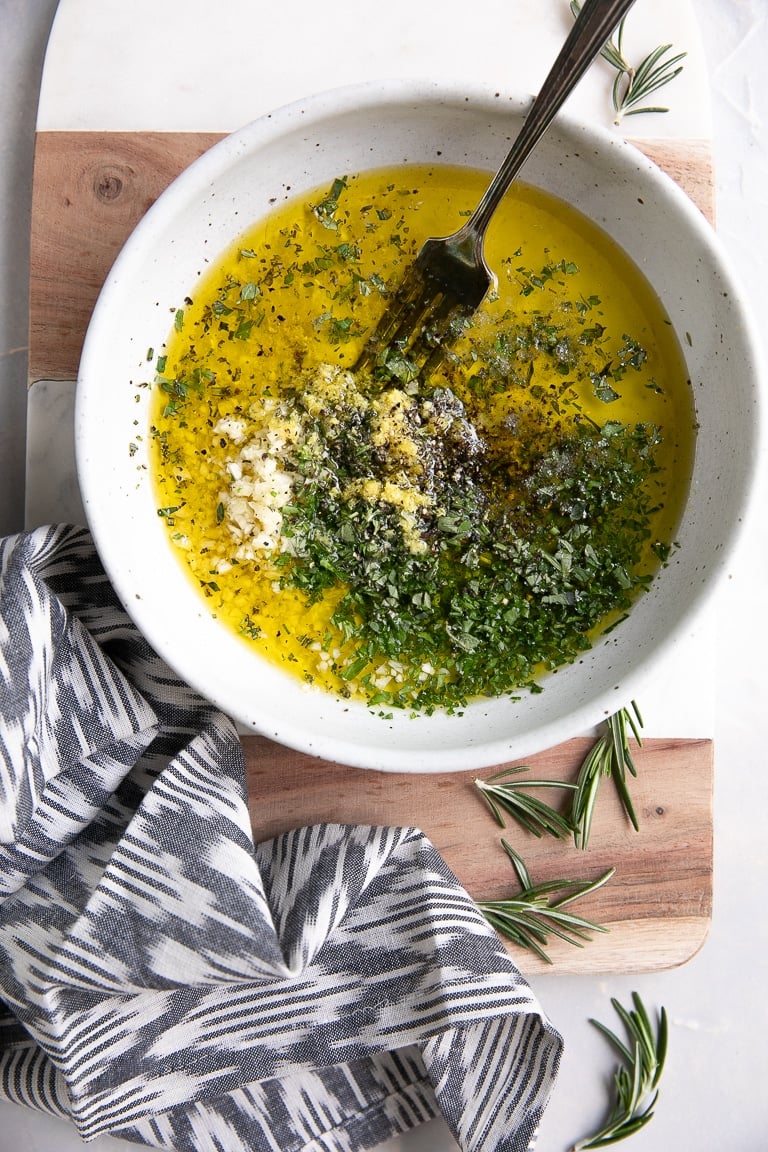 White shallow bowl filled with mixed together ingredients for Greek chicken marinade.