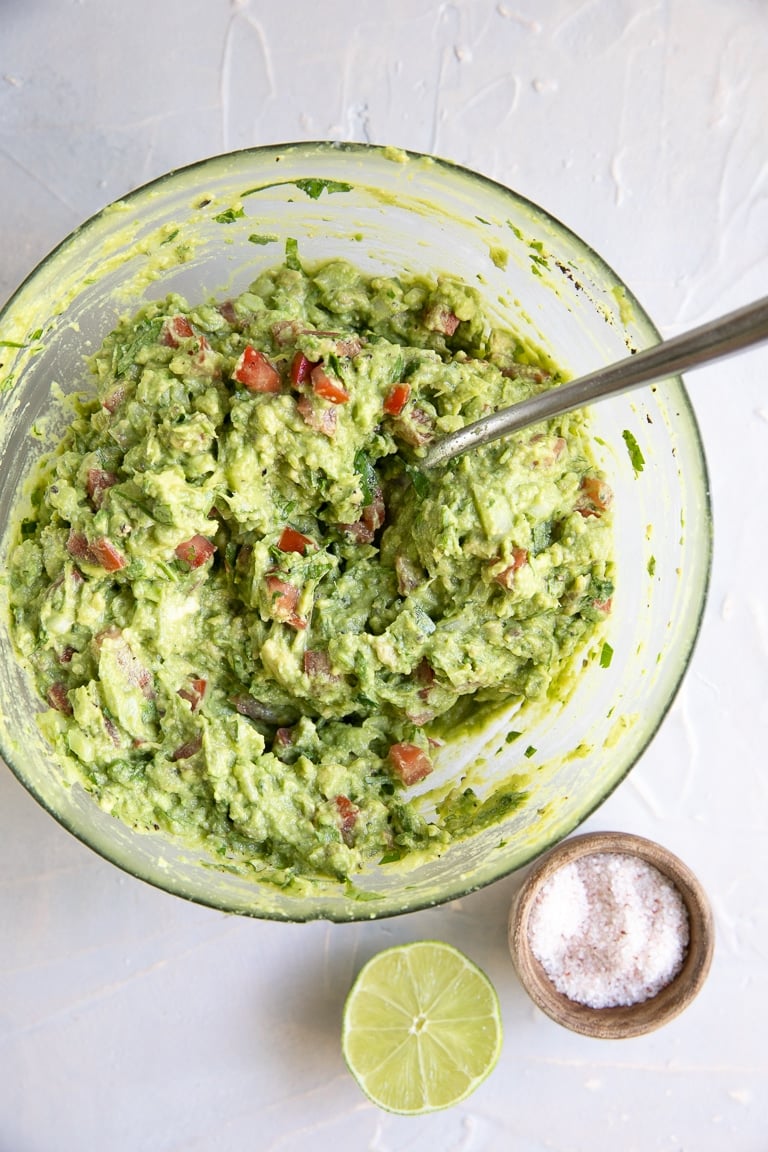 Mixed together guacamole in glass mixing bowl.