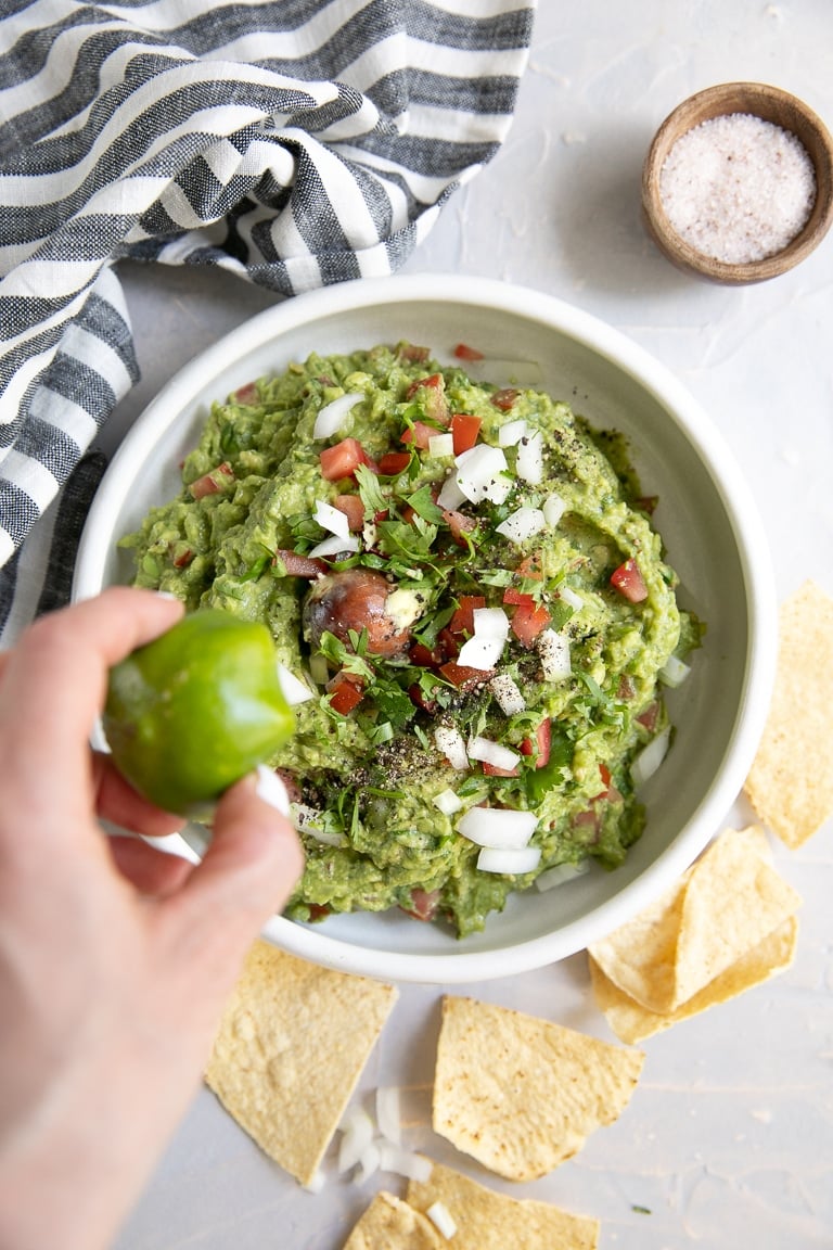 Lime being squeezed onto homemade guacamole.