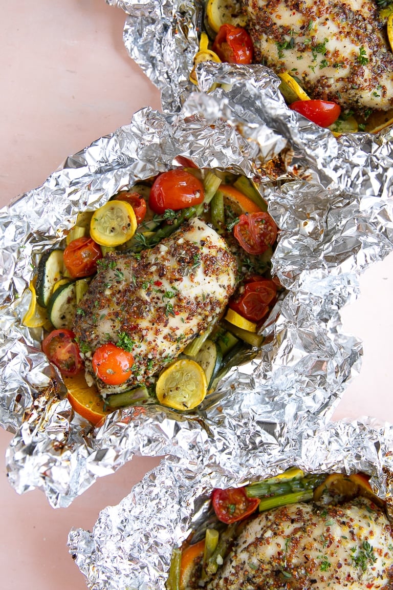 Three foil packets with honey dijon chicken and vegetables.