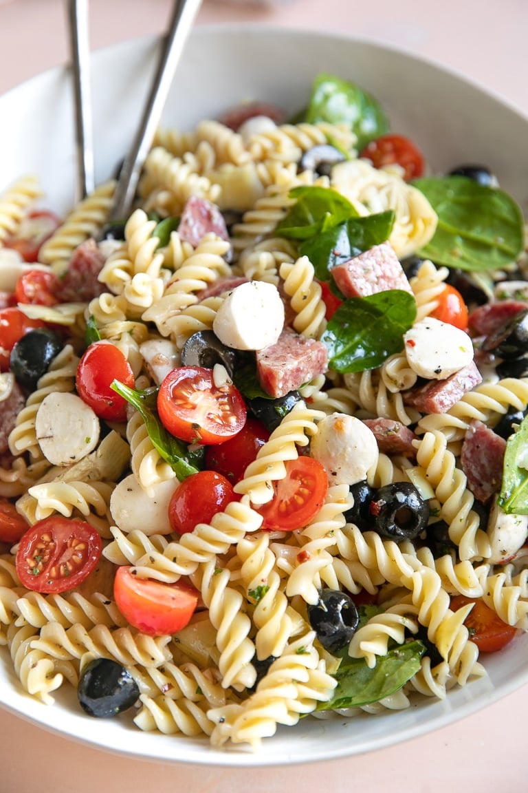 Pasta salad with black olives, salami, spinach, cherry tomatoes, pearl mozzarella.
