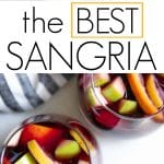 Red wine sangria in a glass pitcher and stemless wine glasses, filled with sliced oranges, apples, lemons, and cinnamon sticks.