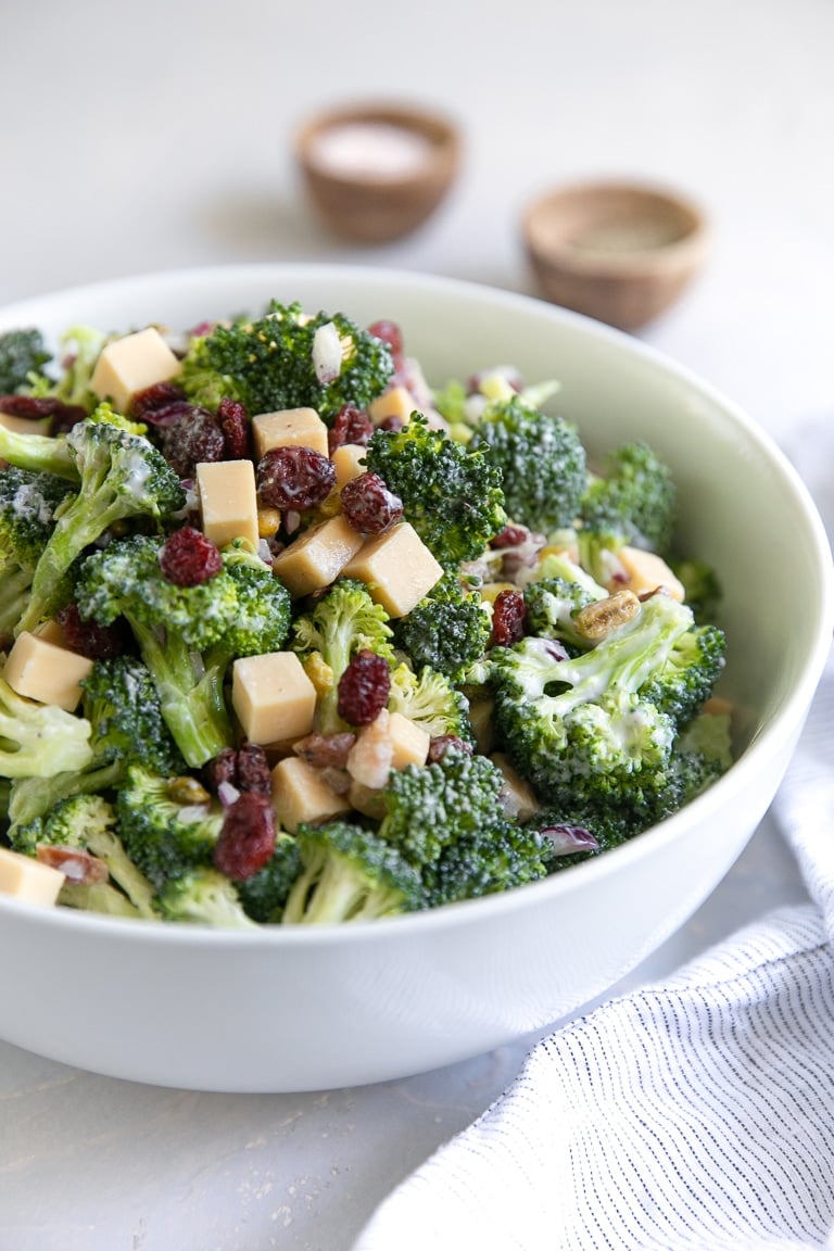 Large bowl filled with mixed together broccoli salad with creamy mayo dressing.