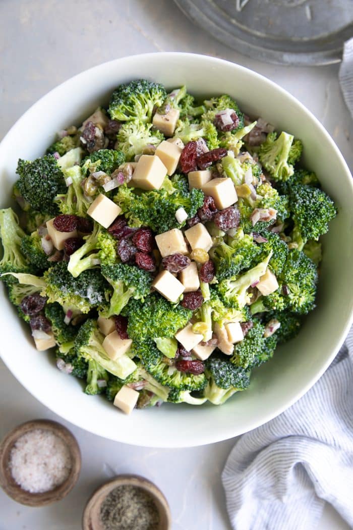 Large bowl filled with mixed together broccoli salad with creamy mayo dressing, bacon, and cranberries..