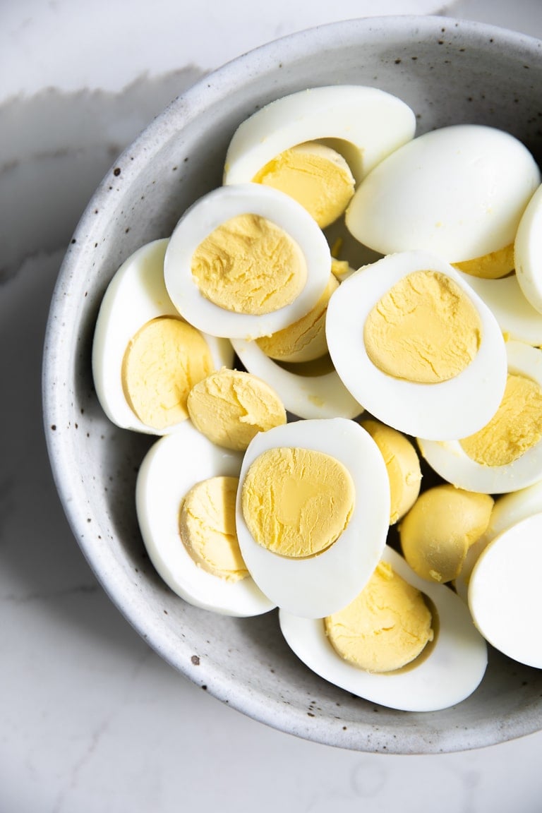 Bowl filled with peeled and halved hard boiled eggs.