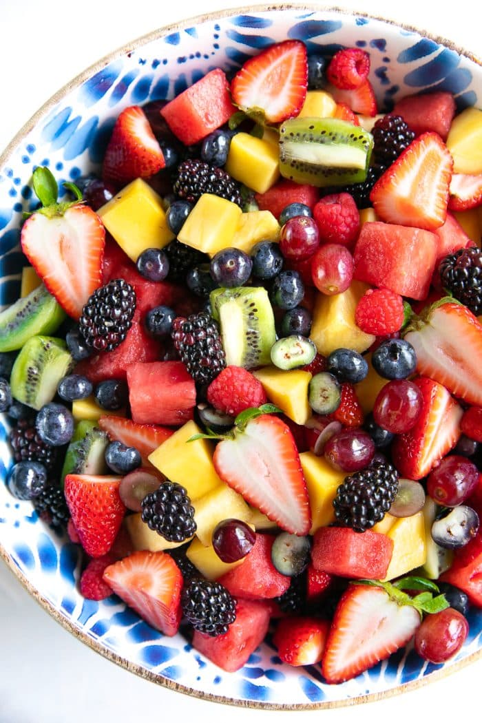 Large salad bowl filled with a variety of different fresh fruit including blackberries, ,strawberries, grapes, pineapple, kiwi, and watermelon.