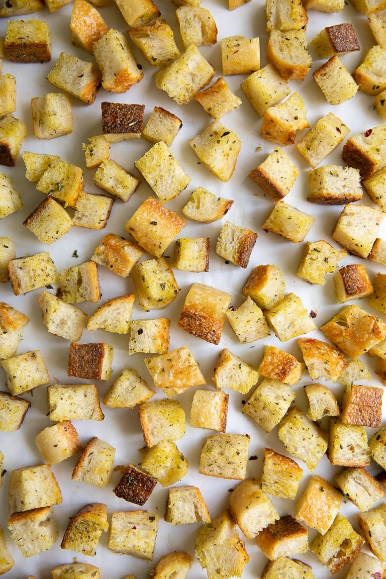Chopped cubes of bread tossed in olive oil, salt, pepper, and Italian seasoning, spread over a large baking sheet.