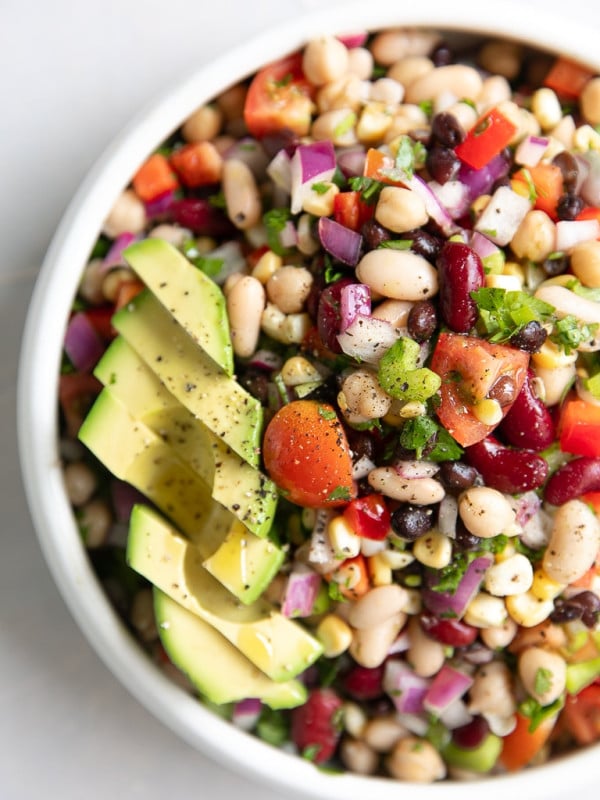 Overhead image of loaded Mexican bean salad topped with sliced avocado.