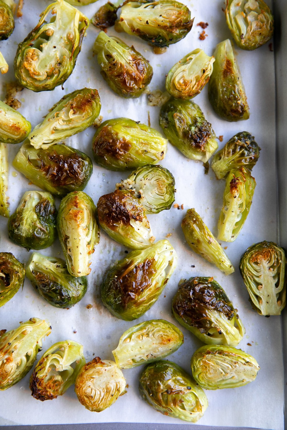 Baking sheet covered with parchment paper and perfectly charred and roasted Brussels sprouts.
