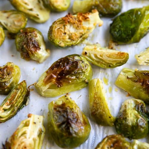 Baking sheet covered with parchment paper and perfectly charred and roasted Brussels sprouts.