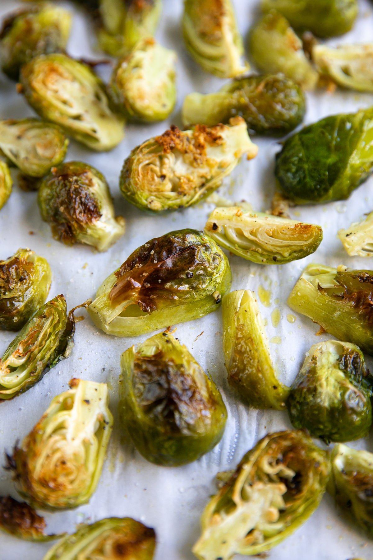 Baking sheet covered with parchment paper and perfectly charred and roasted Brussels sprouts.