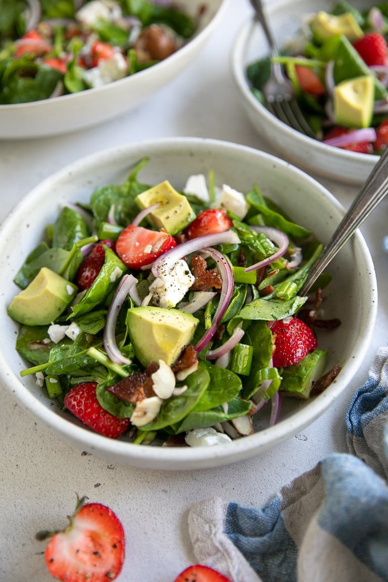 Three single serving salad bowls filled with strawberry spinach salad.