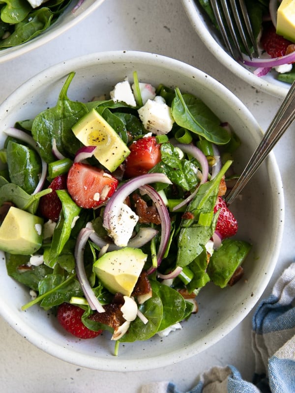 SIngle serving salad bowl filled with strawberry spinach salad.