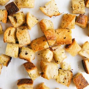 Image of golden crispy homemade croutons on white parchment paper.