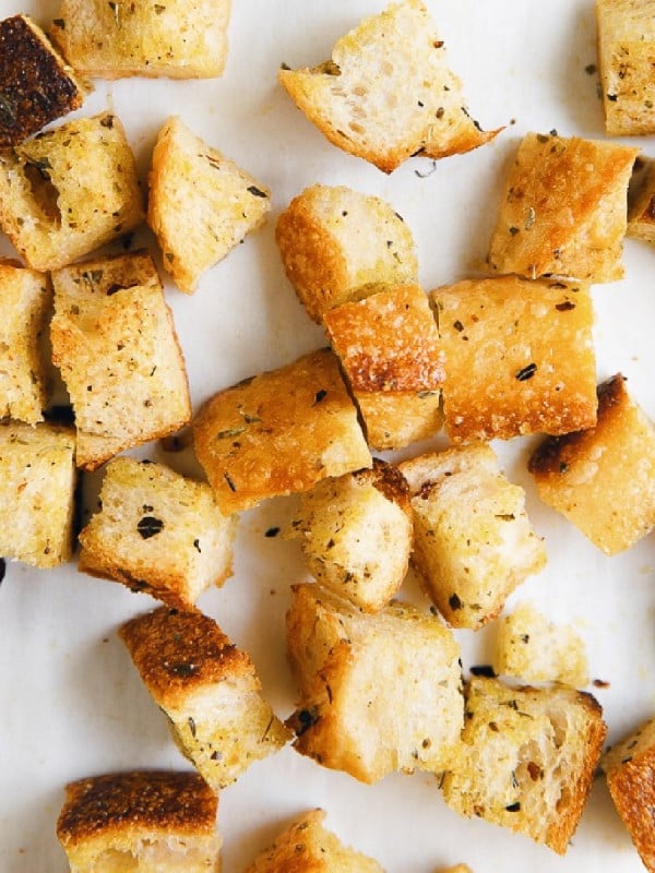 Image of golden crispy homemade croutons on white parchment paper.
