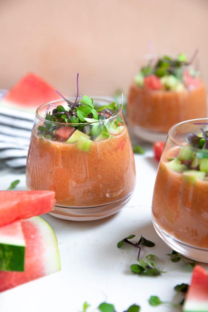 Watermelon gazpacho served in rocks glasses and garnished with fresh microgreens and diced avocado.