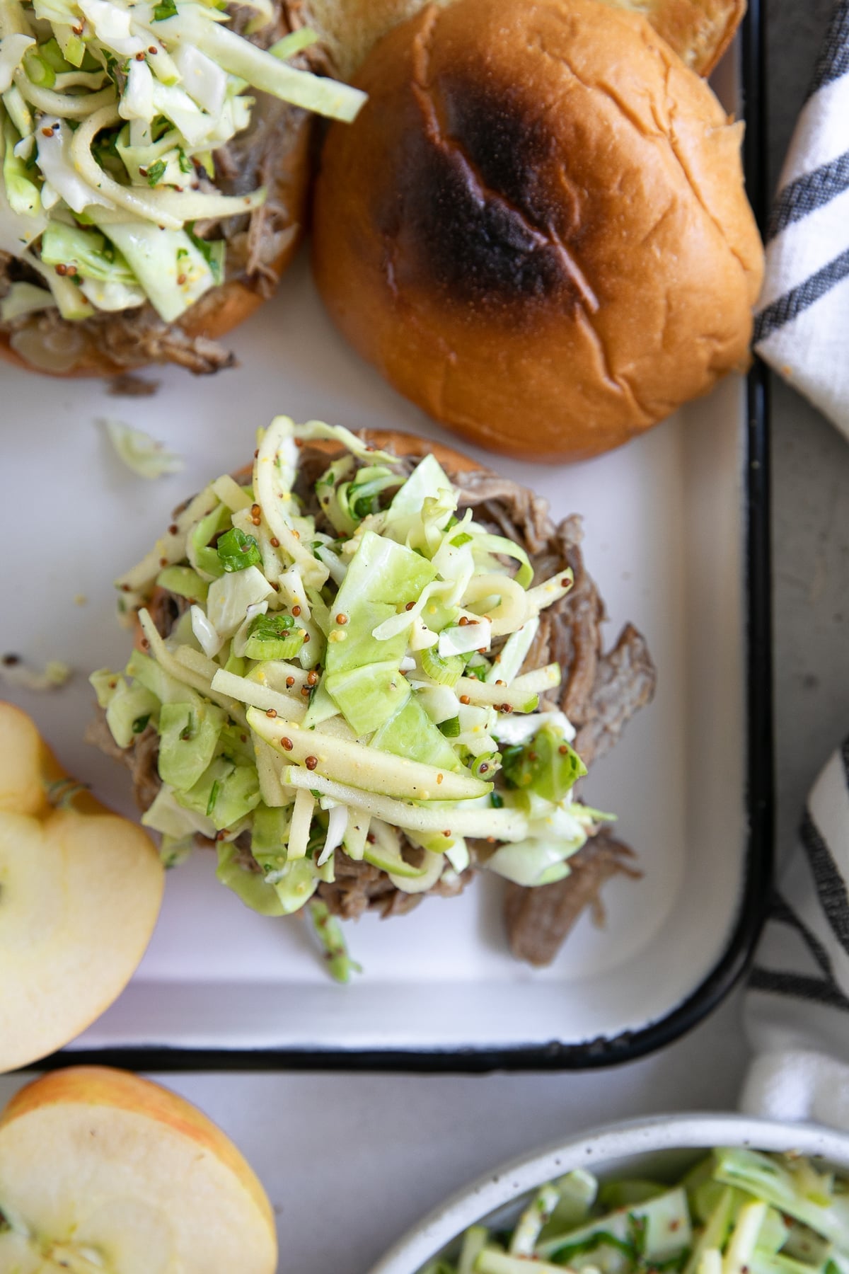 Overhead image of two toasted bums topped with shredded pulled pork and apple slaw.