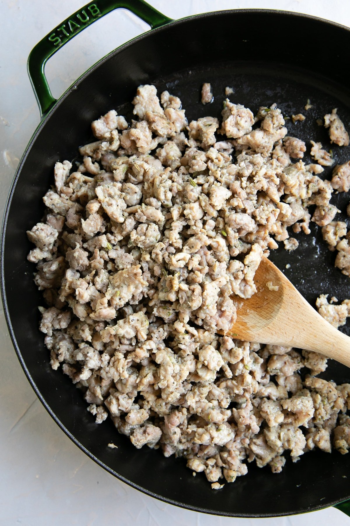 Large skillet filled with ground Italian sausage.