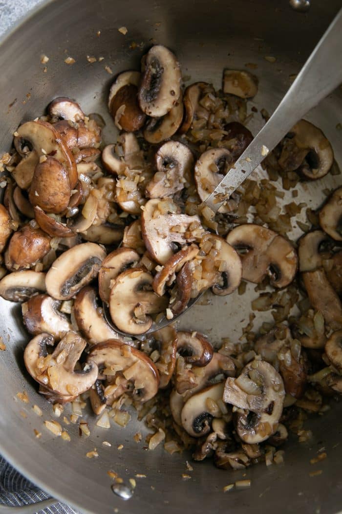Large skillet filled with cooked onions, garlic, and mushrooms.