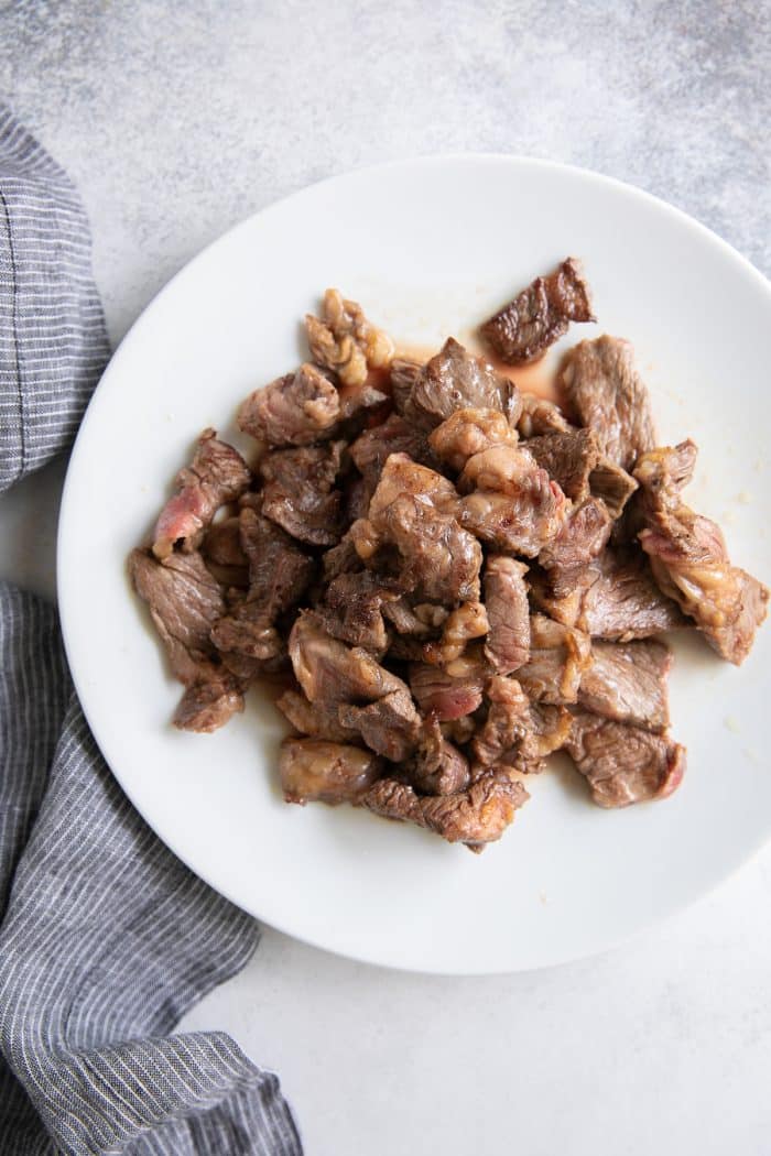 Thinly sliced pieces of cooked beef on a white plate.