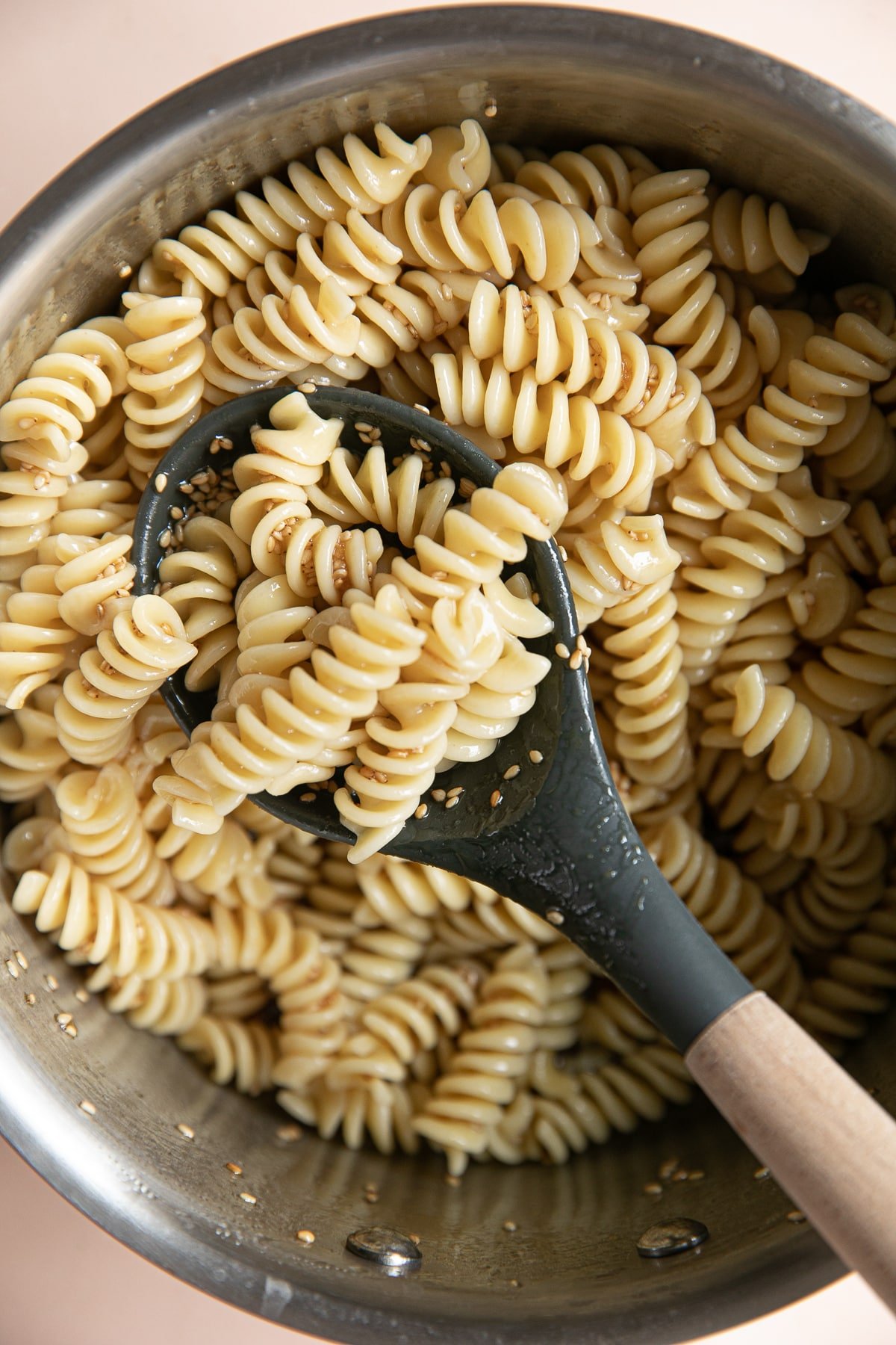 Sauce pot filled with cooked rotini pasta tossed in homemade sesame dressing.
