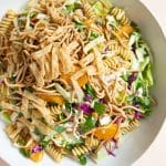 Large salad bowl filled with tossed together Asian pasta salad.