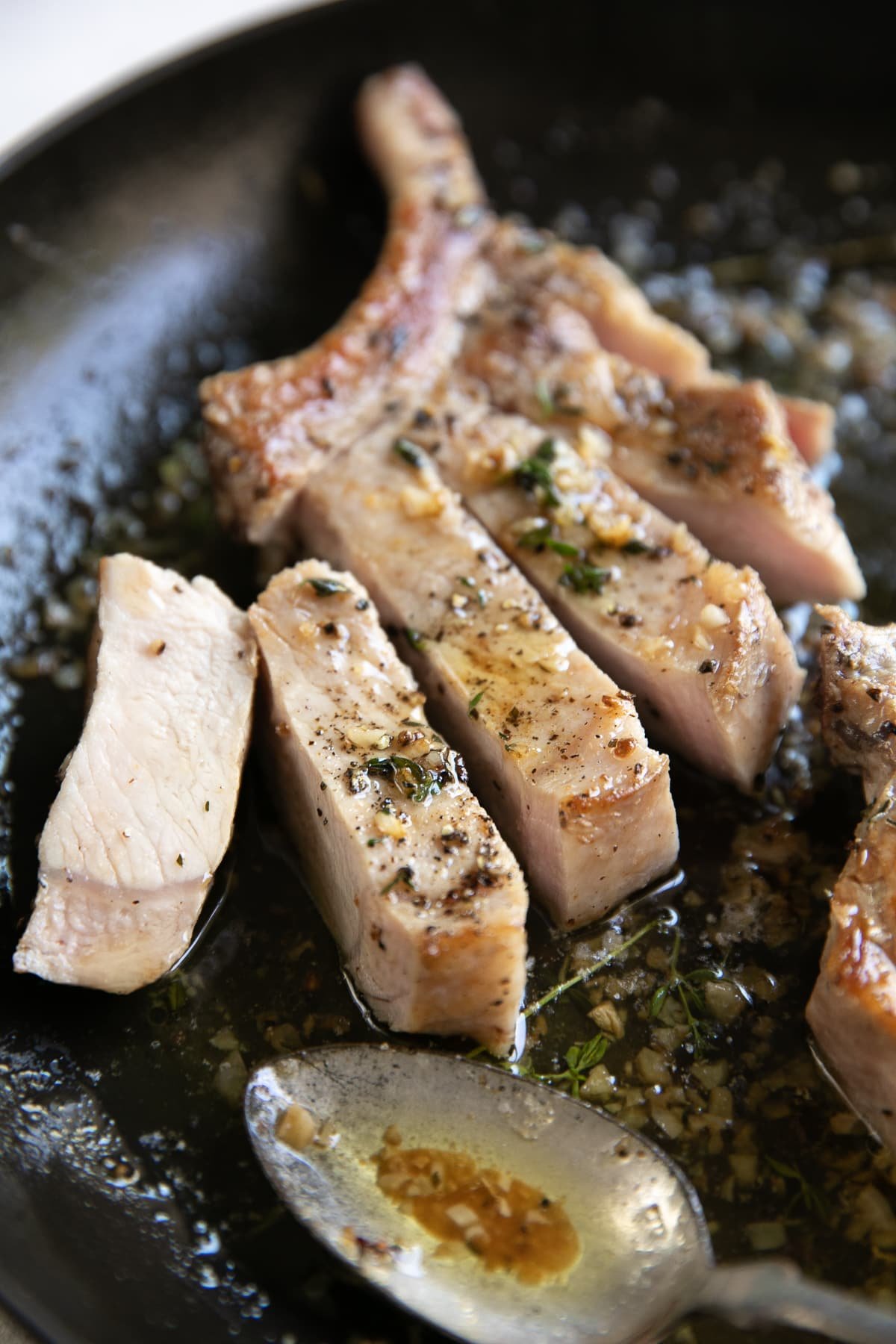 Sliced bone-in pork chop in a black skillet.