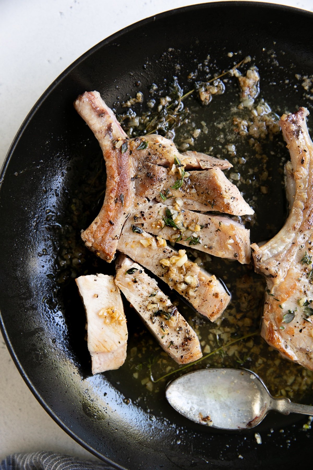 Cooked bone-in pork chop cooked in garlic butter with thyme and sliced into thick pieces.