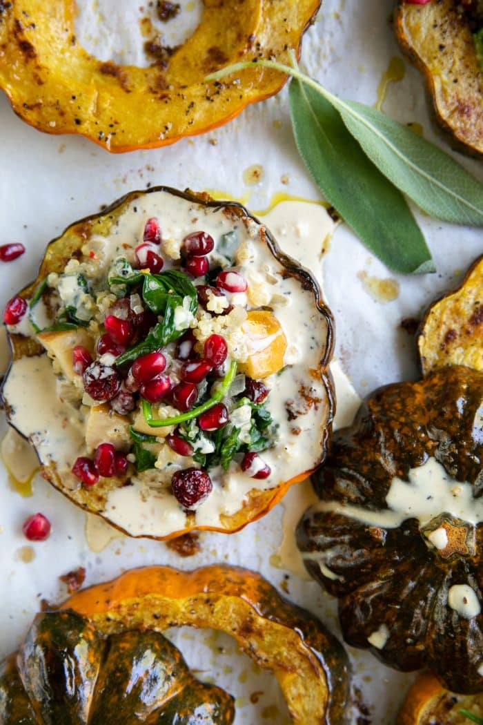 Roasted acorn squash rings topped with a quinoa, apple, spinach, and dried cranberry stuffing, topped with pomegranates, and drizzled with tahini dressing.