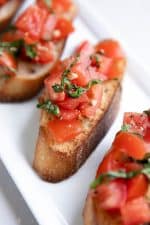 Bruschetta recipe topped with olive oil topped with tomatoes, garlic, and basil.